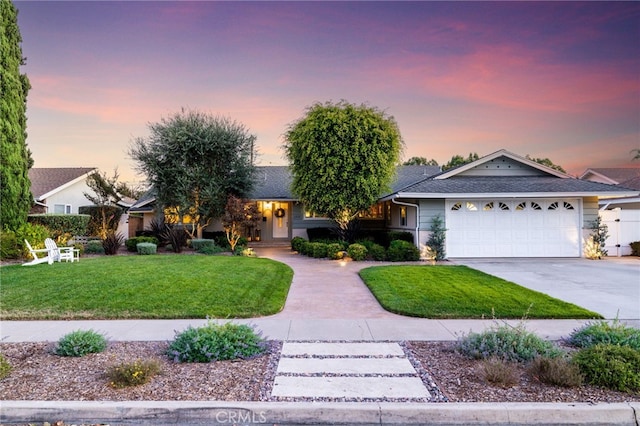 single story home featuring a garage, a yard, and concrete driveway