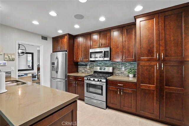 17892 Wellington Ave, North Tustin, CA 92780 - kitchen featuring stainless steel appliances, decorative backsplash, a sink, recessed lighting, and light countertops