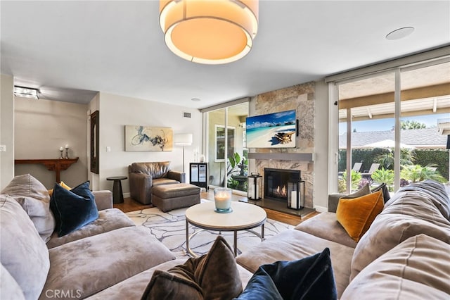 living room featuring expansive windows, visible vents, a large fireplace, and wood finished floors