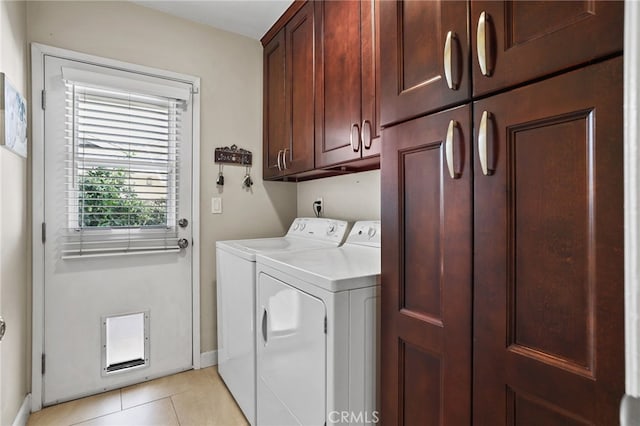 laundry room with baseboards, light tile patterned flooring, cabinet space, and washer and clothes dryer
