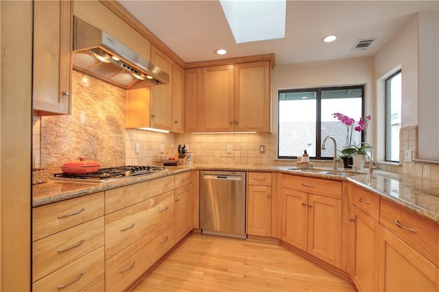 kitchen featuring light wood finished floors, a sink, visible vents, under cabinet range hood, and appliances with stainless steel finishes