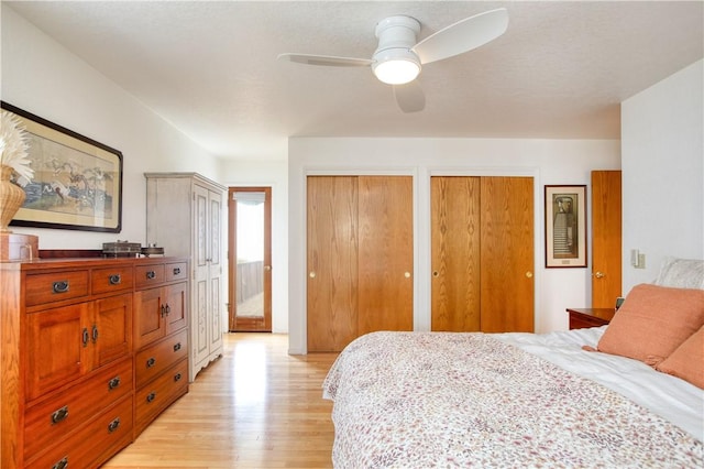 bedroom featuring ceiling fan, light wood-style floors, and two closets