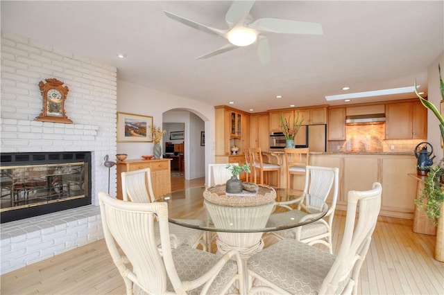 dining space with arched walkways, a ceiling fan, light wood-style floors, and recessed lighting