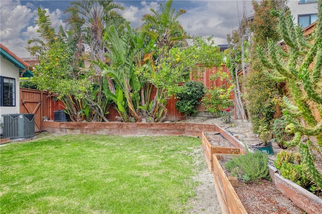 view of yard featuring fence, a vegetable garden, and cooling unit