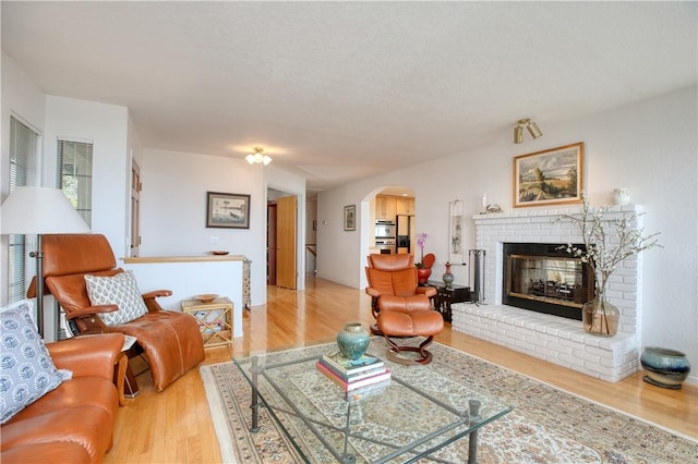 living area featuring arched walkways, wood finished floors, and a fireplace