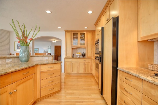 kitchen featuring recessed lighting, light brown cabinetry, oven, black fridge with ice dispenser, and light wood-style flooring