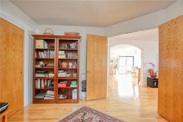 corridor featuring light wood-type flooring and arched walkways