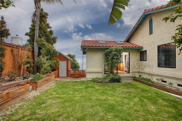 rear view of house featuring a storage shed, a tiled roof, a vegetable garden, fence, and a yard