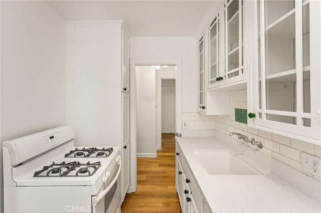455 E Ocean Blvd Unit 411, Long Beach, CA 90802 - kitchen featuring white range with gas stovetop, a sink, white cabinets, light wood-style flooring, and backsplash