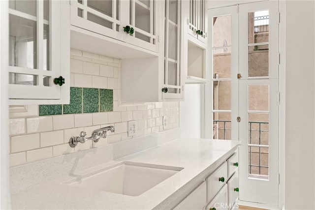 455 E Ocean Blvd Unit 411, Long Beach, CA 90802 - kitchen with a sink, white cabinets, decorative backsplash, and glass insert cabinets