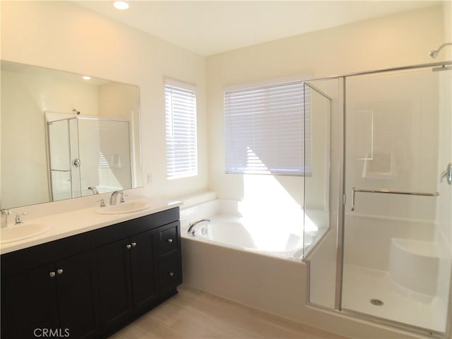 full bath with a sink, a bath, and a shower stall