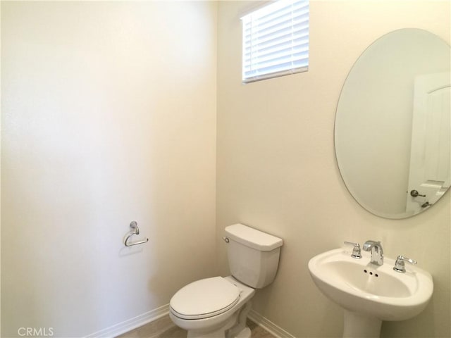 bathroom featuring baseboards, a sink, and toilet