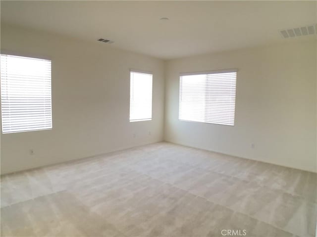 spare room featuring light colored carpet and visible vents