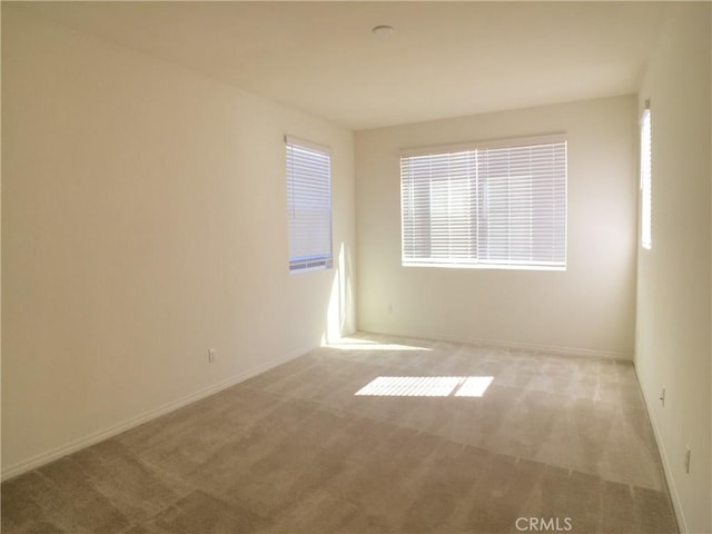 spare room with baseboards and carpet floors