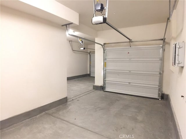 garage featuring baseboards, electric panel, and a garage door opener