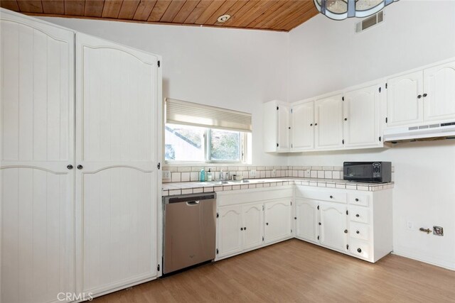 42135 San Francisquito Canyon Rd, Green Valley, CA 91390 - kitchen with stainless steel dishwasher, black microwave, under cabinet range hood, tile counters, and white cabinets
