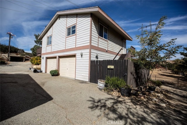 42135 San Francisquito Canyon Rd, Green Valley, CA 91390 - view of home's exterior featuring an attached garage, asphalt driveway, and fence