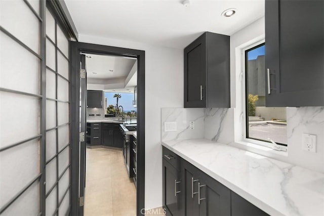 33961 Granada Dr, Dana Point, CA 92629 - kitchen with decorative backsplash, light stone counters, dark cabinetry, and light tile patterned floors
