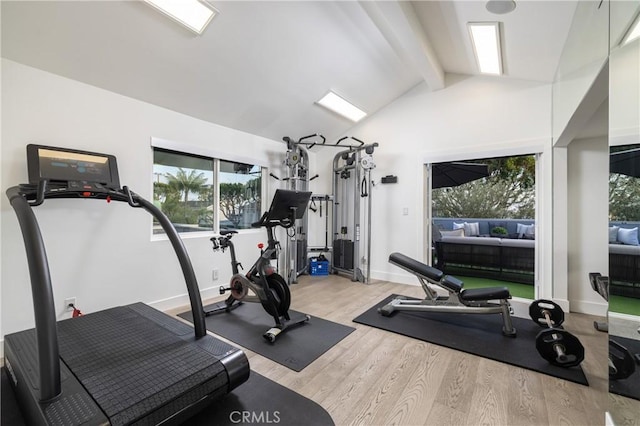 workout room with baseboards, vaulted ceiling, and wood finished floors