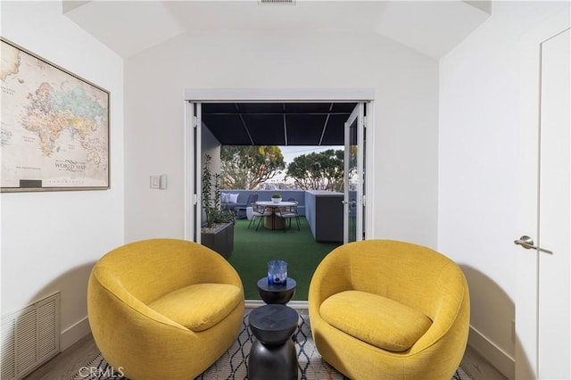 sitting room with baseboards, lofted ceiling, and visible vents