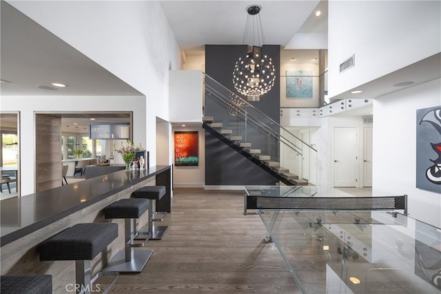 game room with visible vents, a high ceiling, wood finished floors, and a chandelier