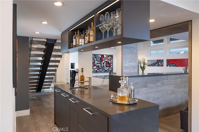 bar featuring stairs, a sink, dark wood-type flooring, a dry bar, and recessed lighting