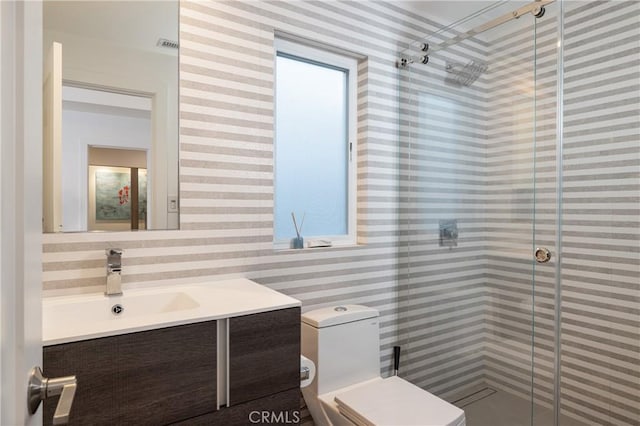 bathroom featuring toilet, vanity, and a shower stall