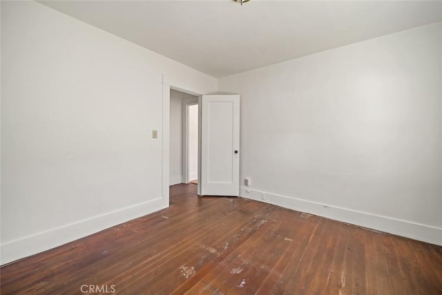 spare room with baseboards and hardwood / wood-style floors