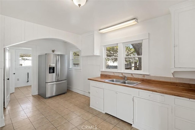 kitchen featuring a sink, stainless steel fridge with ice dispenser, wooden counters, and a healthy amount of sunlight
