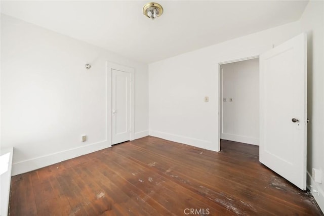 unfurnished room featuring wood-type flooring and baseboards