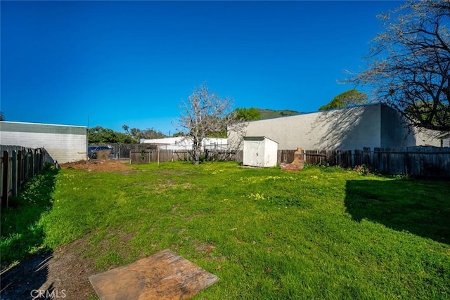 view of yard with an outdoor structure, a fenced backyard, and a shed