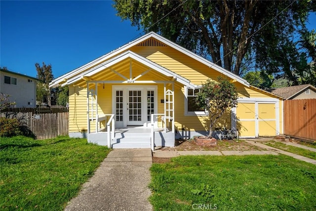 bungalow-style home featuring a storage unit, a front lawn, fence, and a porch
