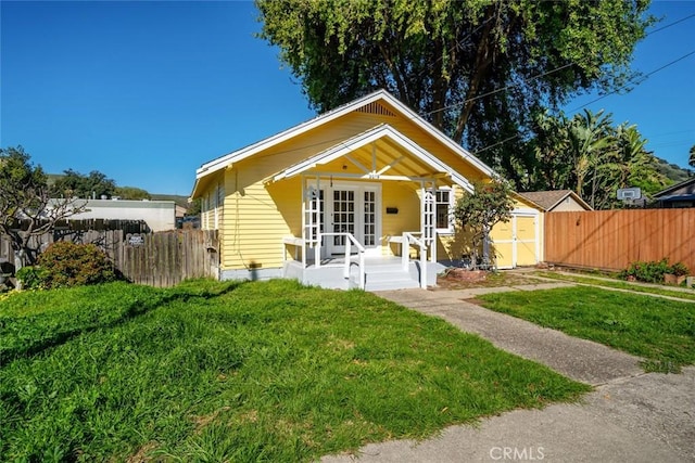 bungalow with a shed, fence, covered porch, and a front yard