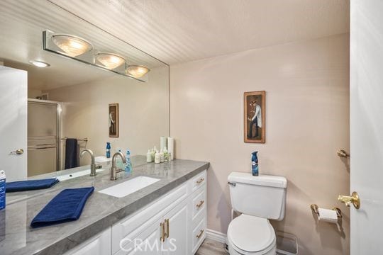 bathroom featuring toilet, vanity, and an enclosed shower