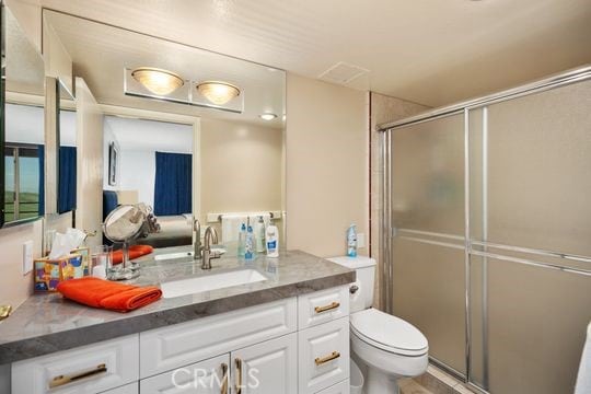 bathroom with a stall shower, toilet, and vanity