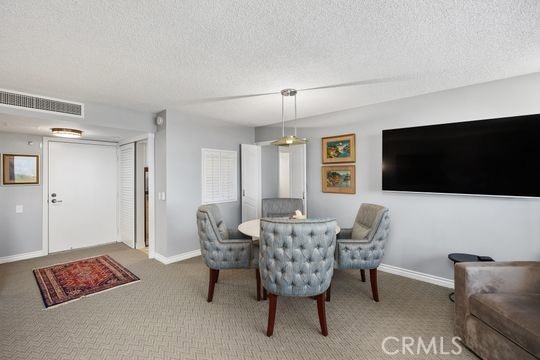 carpeted dining space with baseboards, visible vents, and a textured ceiling