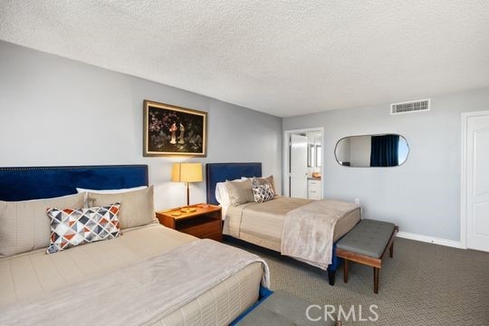 carpeted bedroom with a textured ceiling, baseboards, and visible vents