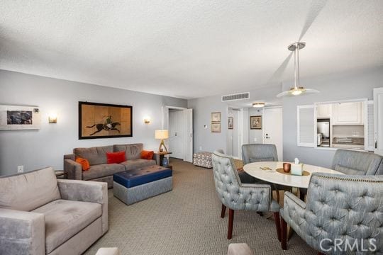 living area with carpet flooring, a textured ceiling, ceiling fan, and visible vents