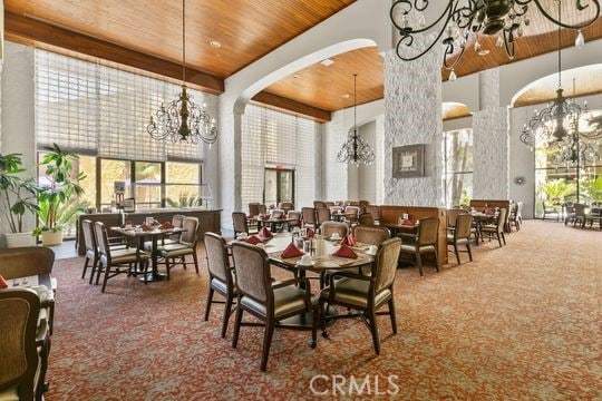 dining room with a notable chandelier, wooden ceiling, a towering ceiling, and carpet flooring