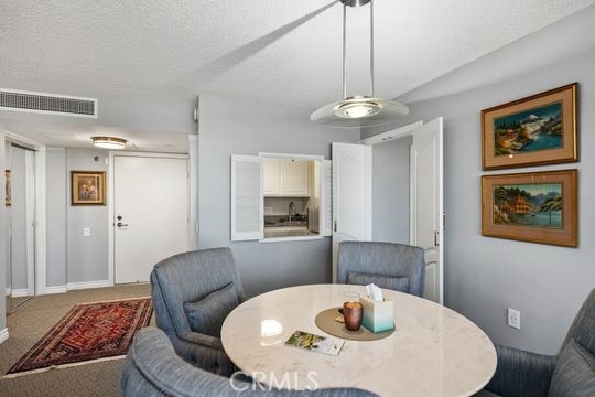 dining space featuring carpet floors, a textured ceiling, and visible vents