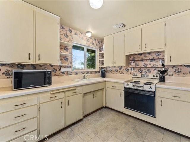20510 Duryee Ln, Redding, CA 96002 - kitchen with white electric range oven, light countertops, black microwave, open shelves, and a sink