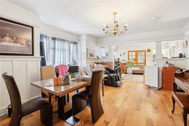 dining space featuring a decorative wall, a wealth of natural light, light wood-style flooring, and a chandelier