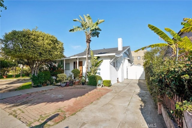 view of front of house featuring a gate, stucco siding, and a chimney