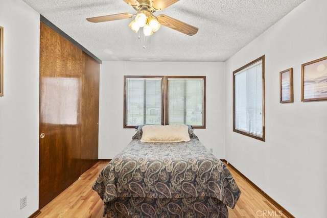 bedroom with a textured ceiling, wood finished floors, and ceiling fan