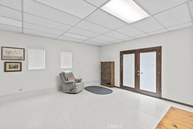 living area with baseboards, french doors, and a paneled ceiling