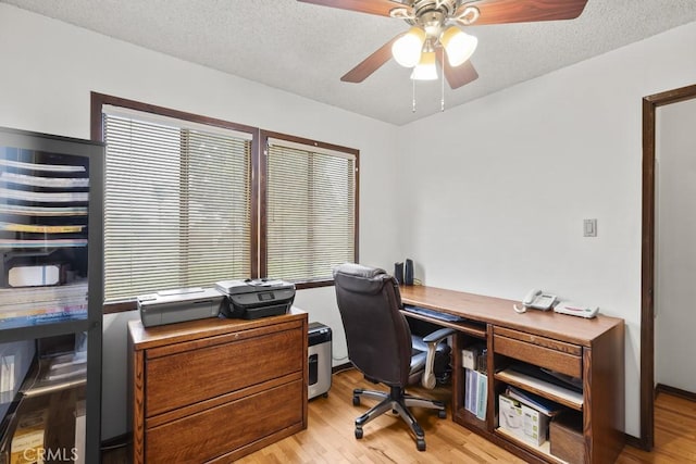 office space with a textured ceiling, light wood-type flooring, and a ceiling fan