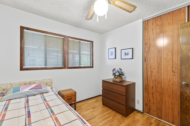 bedroom with a closet, a textured ceiling, a ceiling fan, and light wood finished floors