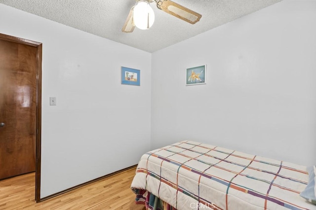 bedroom featuring a ceiling fan, light wood-style flooring, and a textured ceiling