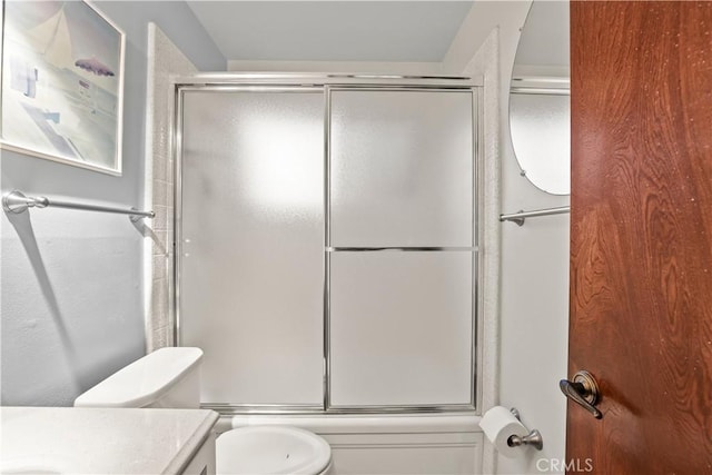 bathroom with combined bath / shower with glass door, toilet, and vanity