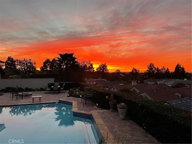 pool at dusk featuring a patio area